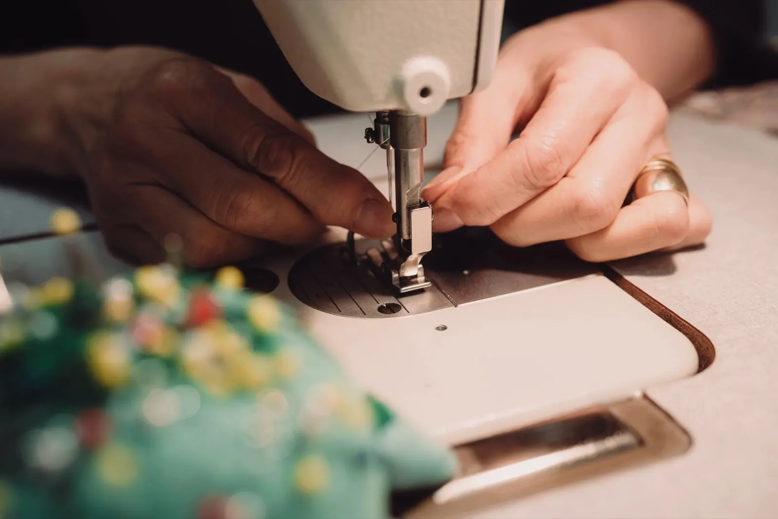 Close-up of hands guiding fabric beneath a sewing machine needle